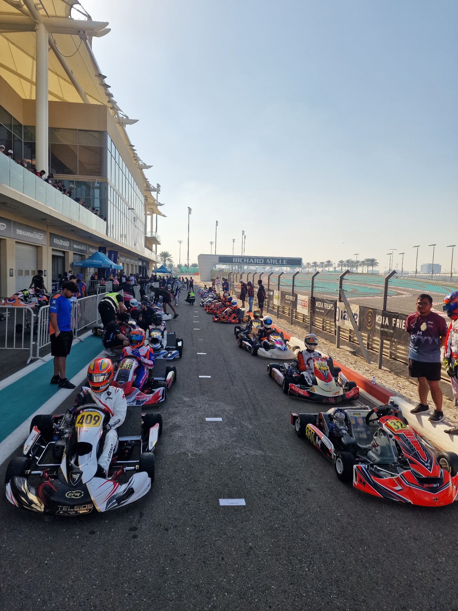 Ambiente internacional de karting con pilotos y karts en Yas Marina, Emiratos Árabes Unidos.